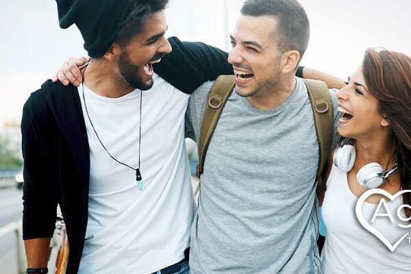 Three people smiling on a bridge, wearing casual clothing.