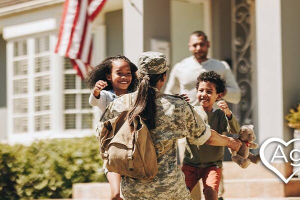 Person in military uniform embracing two smiling children.