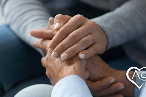 Hands clasped together, logo with heart shape and text Agape Treatment Center.