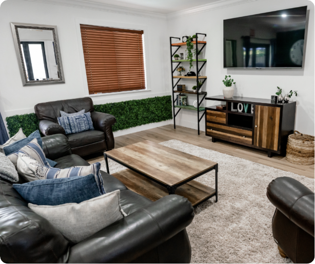 Living room with leather sofas, wooden coffee table, wall-mounted TV, and decorative shelves.