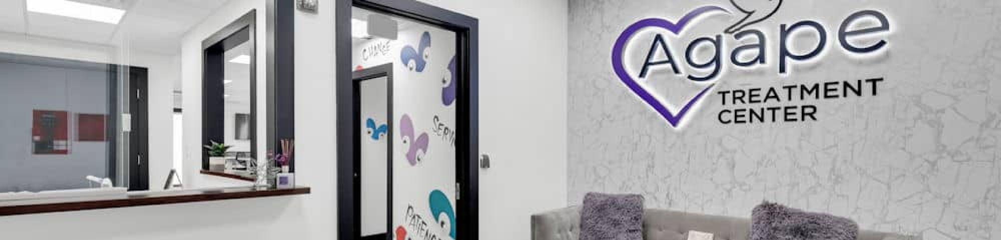 Agape Treatment Center lobby with modern decor and logo on a marbled wall.