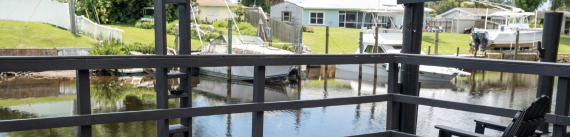 Deck overlooking a canal with multiple boats and houses in the background.